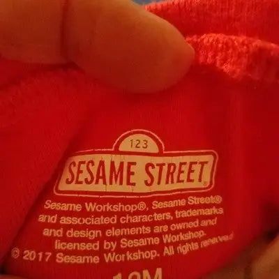 Red fabric with a white Sesame Street logo on Sesame Street Elmo & Cookie Monster 2-piece pajamas size 12M
