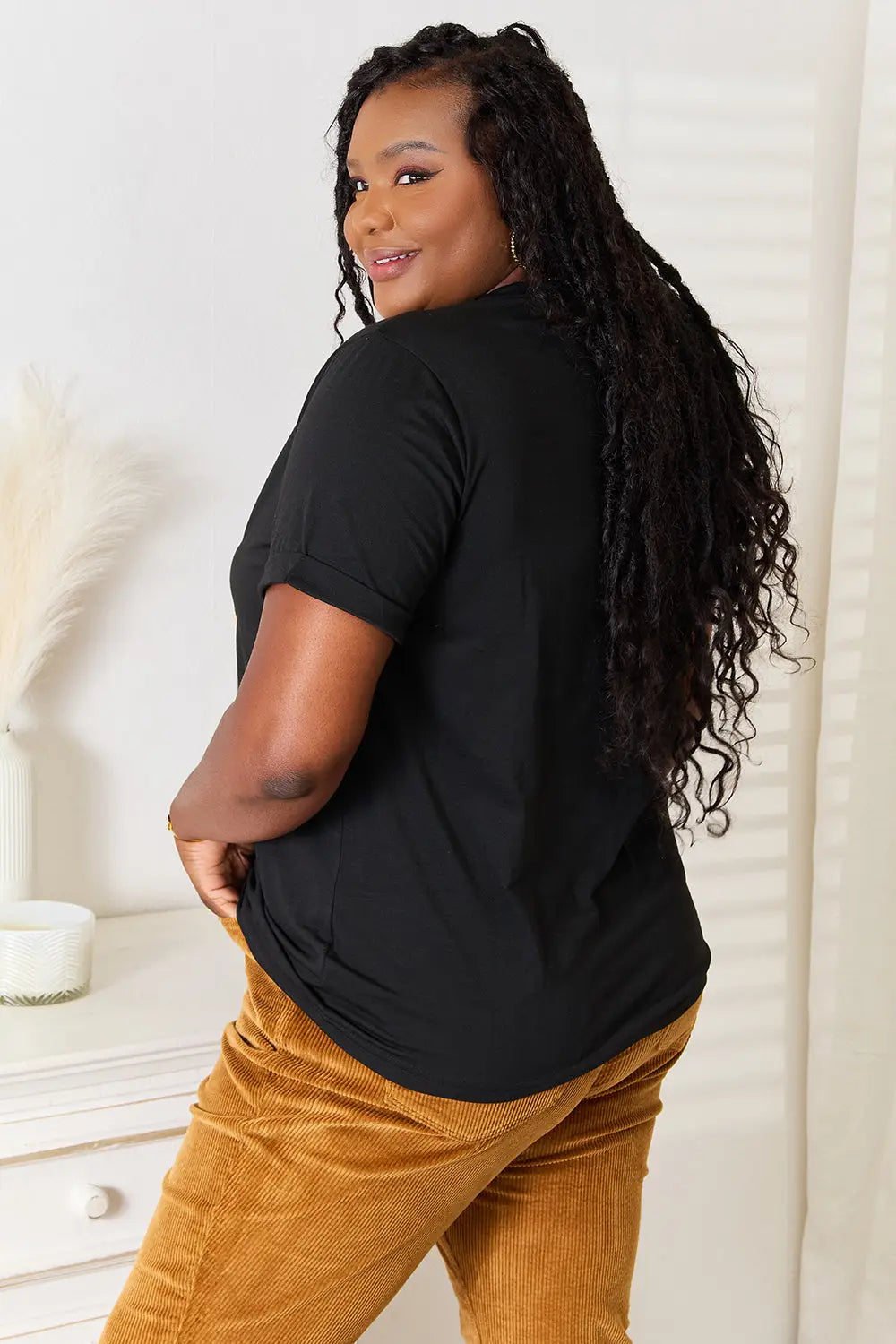 Black short-sleeved top with round neck and kind graphic design paired with mustard corduroy pants