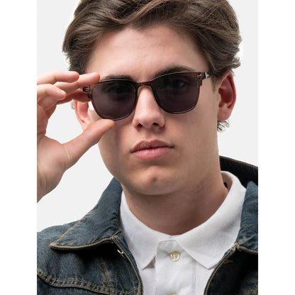Young man wearing Smooder sunglasses with brown frames, white polo, and denim jacket