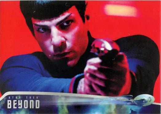 Man with pointed ears in blue uniform aiming futuristic weapon on Star Trek promo card