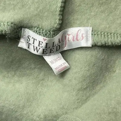 Green fleece fabric with Stella Tweed clothing label on sage green pullover hoodie for girls