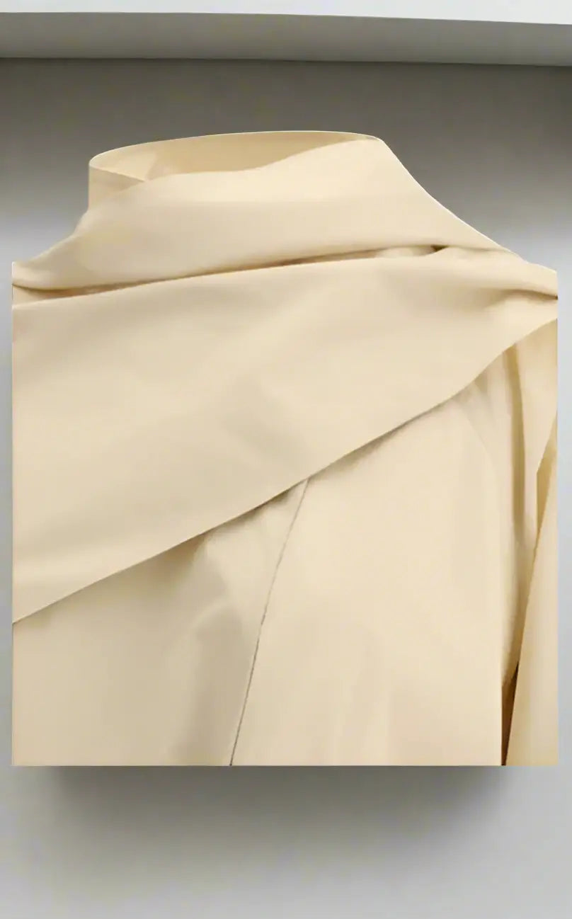 Cream-colored draped top with high collar from THE ROW Donette Trench Coat collection
