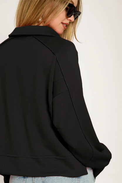 Black cropped blazer with collared neck, oversized sleeves, button closure, and raw hem