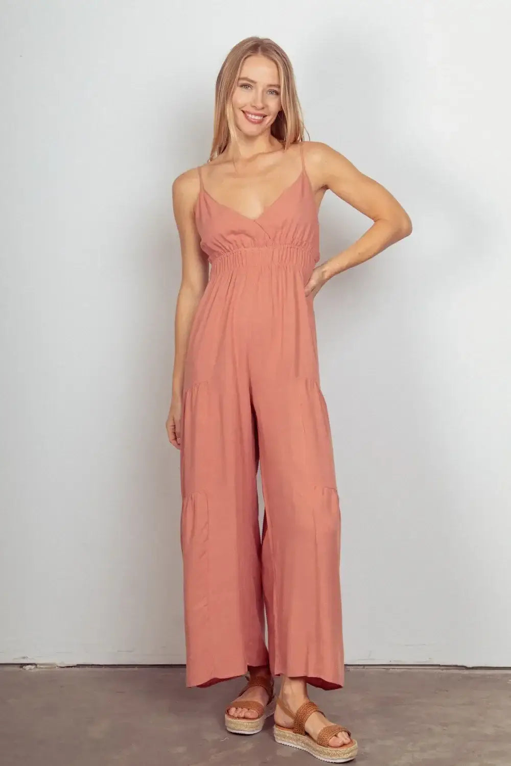 Coral wide leg jumpsuit with adjustable thin straps and subtle pleated texture
