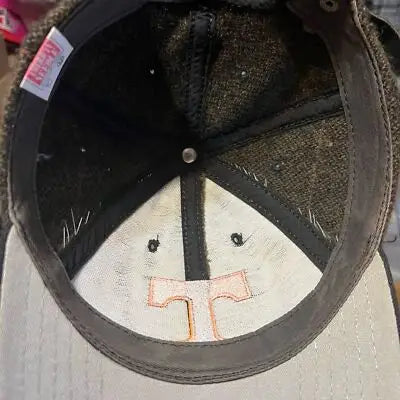 Inside view of a dark brown baseball cap with orange T logo on the brim