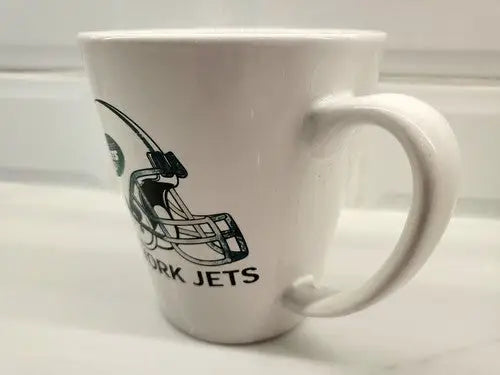White coffee mug featuring New York Jets logo on green ceramic design