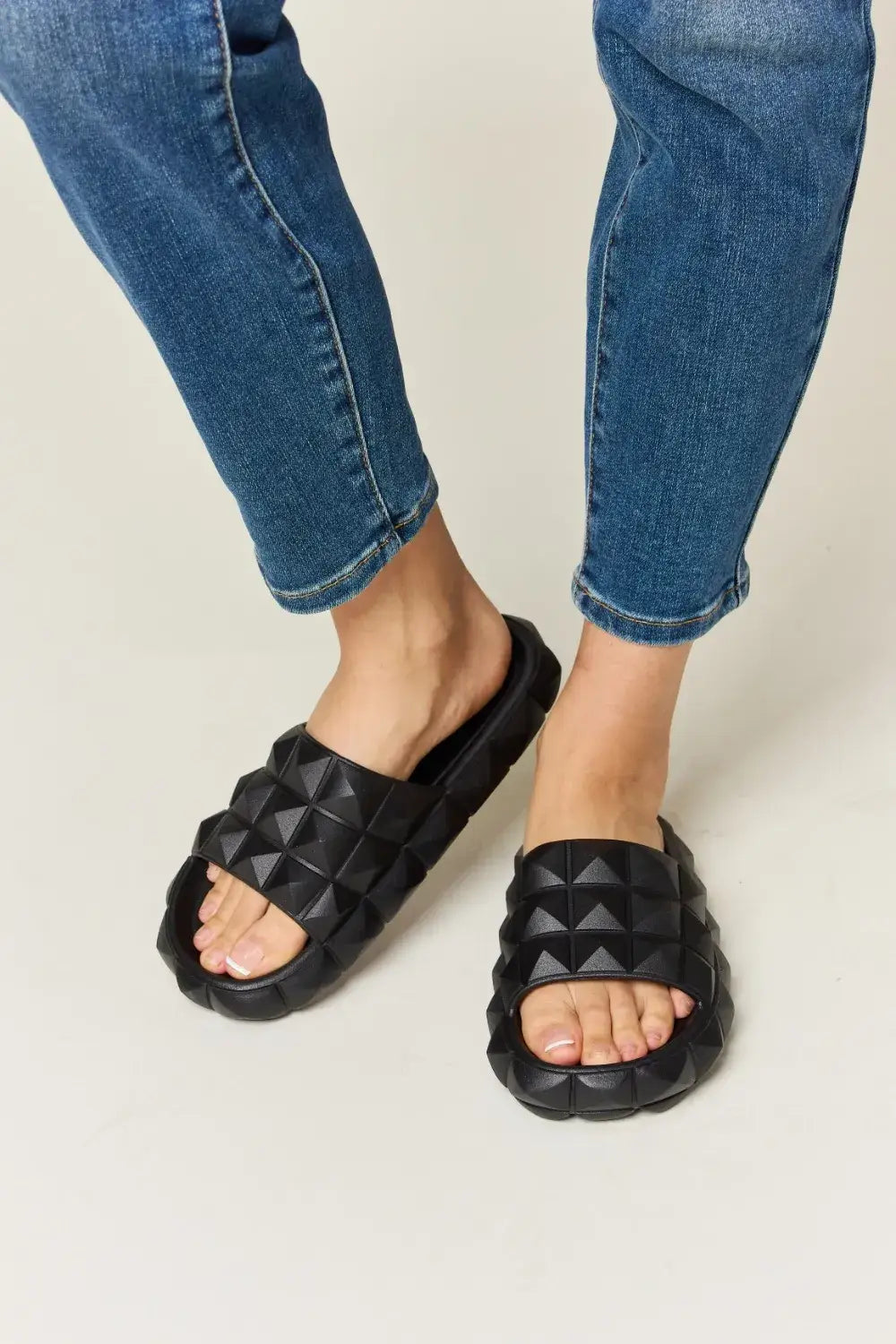 WILD DIVA Pyramid Stud Toe Band Footbed Sandals with black studded slide sandals and blue jeans