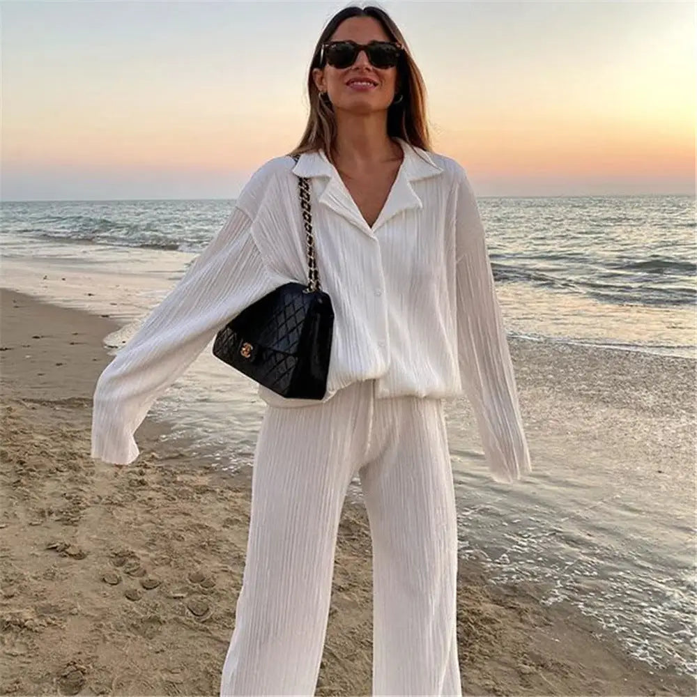 Woman wearing white women tracksuits shirt with long pants two pieces on beach at sunset