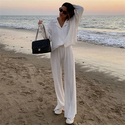 Woman in white women tracksuits shirt with long pants two-piece set holding black quilted handbag