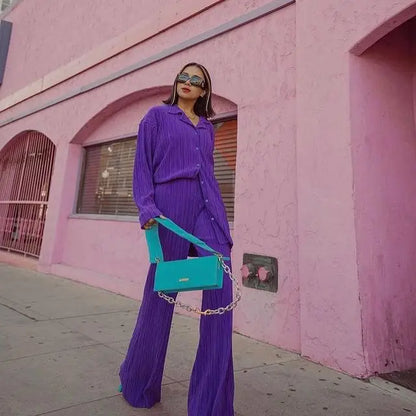 Woman wearing purple women tracksuits shirt with long pants two pieces and teal shoulder bag