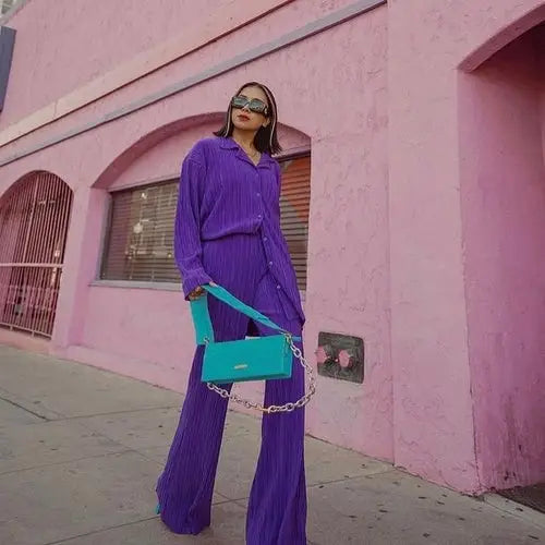 Woman in purple women tracksuits shirt with long pants two-piece set holding teal shoulder bag