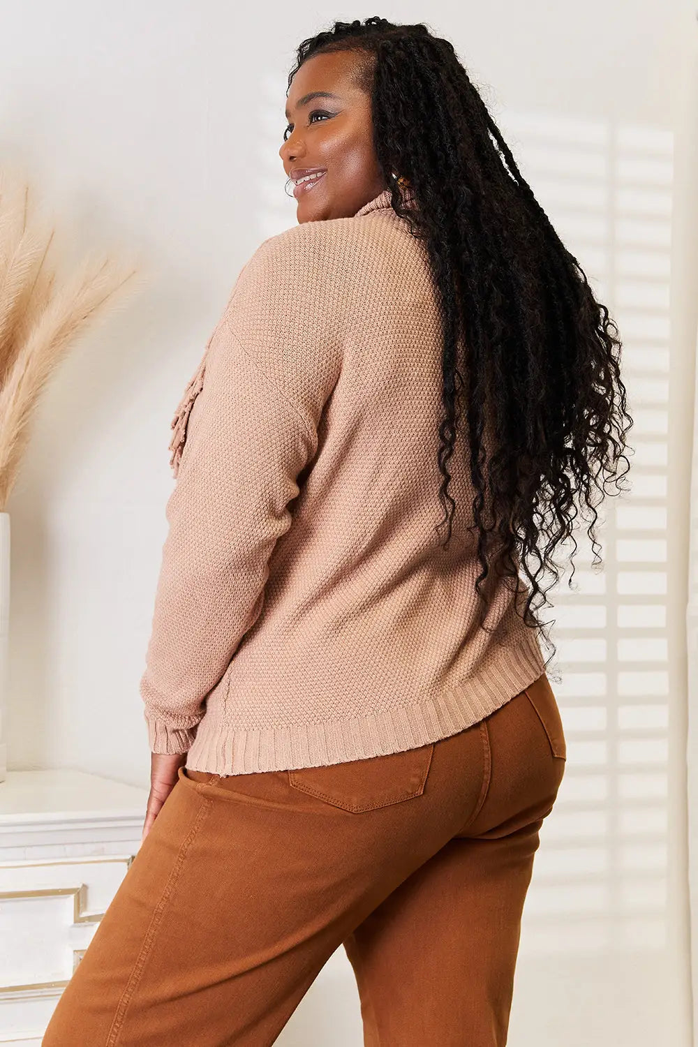 Beige textured long sleeve sweater with turtleneck fringe and braided hair styling