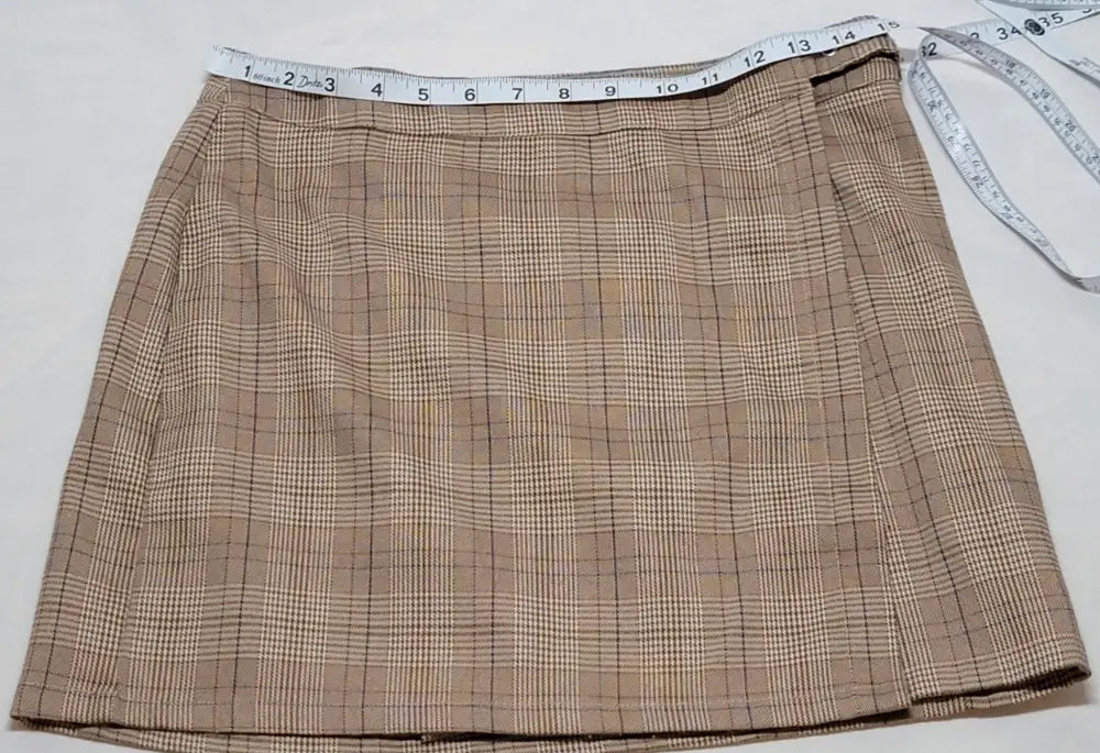 Y2K plaid mini skirt with measuring tape across waist, brown and white plaid design