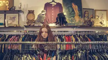 Young woman browsing clothes racks in a thrift store.